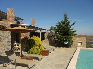 a villa with a swimming pool with chairs and an umbrella at Aigaion House in Otziás