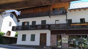 a white building with a balcony on top of it at Appartamenti Kratter Valeria in Sappada