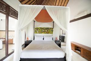 a bedroom with a canopy bed with white curtains at Pondok Anastasia in Ubud +21 photos