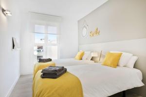 two beds in a room with yellow and white at Mirador del Ebro in Zaragoza