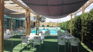 un gruppo di tavoli e sedie accanto a una piscina di Hotel Almagro ad Almagro