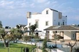 una gran casa blanca con árboles delante de ella en Masseria Chiancone Torricella, en Martina Franca