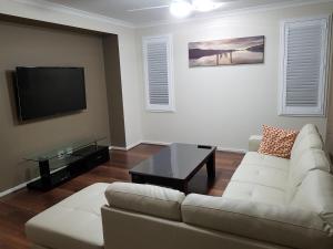 sala de estar con sofá blanco y TV en Jasper Place, en Brisbane