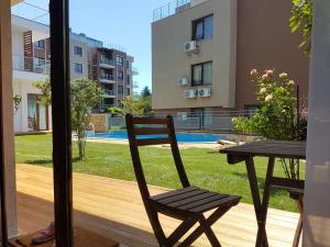 eine Holzterrasse mit einem Tisch und einem Stuhl auf dem Balkon in der Unterkunft Kiara Apartments in Sweti Konstantin
