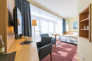 a hotel room with a bed and a desk with a television at Strand-Hotel Hübner in Warnemünde
