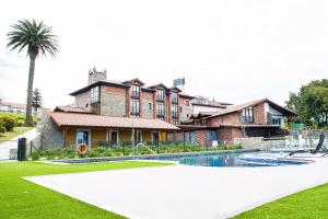 a house with a swimming pool in front of a building at Hotel Marfrei in Hinojedo