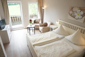 a bedroom with a large bed and a living room at Pension Tüxen in Hasselberg
