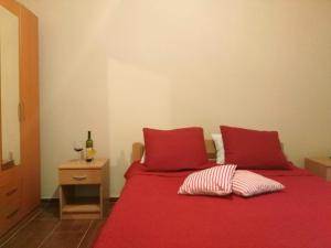 a red bed with two pillows and a bottle of wine at Apartmani Cuce in Kotor