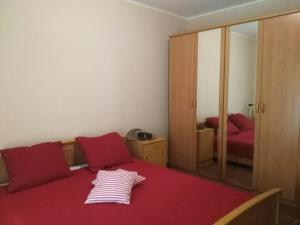 Schlafzimmer mit einem Bett mit roter Bettwäsche und einem Spiegel in der Unterkunft Apartmani Cuce in Kotor
