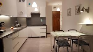 uma cozinha com armários brancos e uma mesa e cadeiras em Apartament Akwarelowy em Kolobrzeg