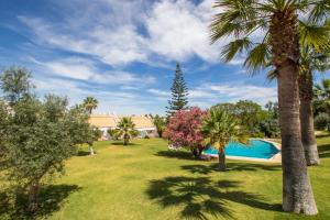 a yard with palm trees and a swimming pool at Capitalmoura Mouragolf Village in Vilamoura