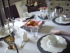 a table with a white table cloth with plates and cups at La maison Maria Rosa in Onzain