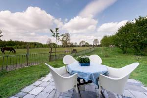 a table with white chairs and a field with horses at Farm Stay Luythoeve in Meeuwen