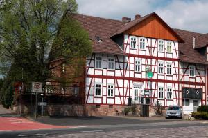 um edifício branco e vermelho com um carro estacionado na frente em Ehlener Poststuben em Habichtswald