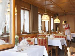 een restaurant met witte tafels en een serveerster op de achtergrond bij derWaldfrieden naturparkhotel in Herrenschwand
