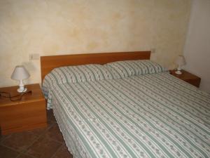 ein Schlafzimmer mit einem Bett mit gestreifter Bettdecke und zwei Lampen in der Unterkunft Lindavacanza in Moneglia