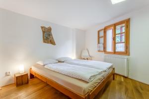 a white bedroom with a large bed and a window at Apartments No.59 Loket in Loket