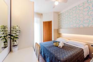 um quarto de hotel com uma cama com um cobertor azul em Hotel Seven em Rimini