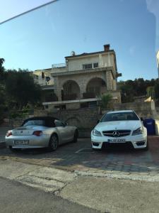 two cars parked in a parking lot in front of a house at Apartments By The Sea in Pula