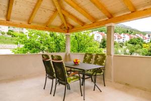 a table and chairs on a balcony with a wooden roof at Dubravka apartmani in Mokošica