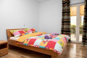 a bedroom with a bed with a colorful quilt at Dubravka apartmani in Mokošica