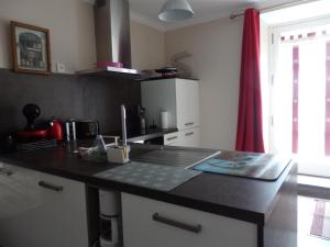 a kitchen with a black counter top and a red curtain at La Maison De Béatrice in Murat +13 photos