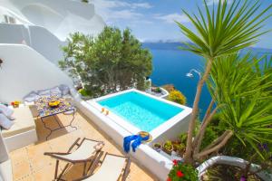 a pool on the side of a house with a palm tree at Ifestio Villas Oia in Oia