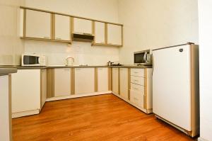 La cuisine est équipée de placards blancs et d'un réfrigérateur blanc. dans l'établissement Jetty Suites Apartments, à Malacca
