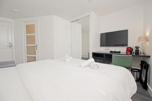 a white bedroom with a white bed and a desk at Guesthouse Prinsencanal 2 in Amsterdam