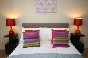 ケンブリッジにあるSignet Apartments - The Triangleの赤いランプ2つとカラフルな枕2つ付きのベッド1台