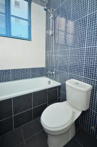 a bathroom with a white toilet and a bath tub at Jetty Suites Apartments in Malacca