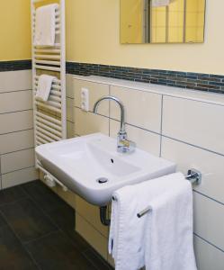ein Badezimmer mit einem weißen Waschbecken und Handtüchern in der Unterkunft Apartments Golfpark Schlossgut Sickendorf in Lauterbach