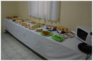 een witte tafel met borden voedsel erop bij Hotel Master in Primavera do Leste