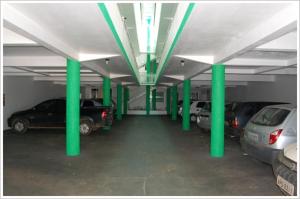 a parking garage with green columns and cars in it at Hotel Master in Primavera do Leste