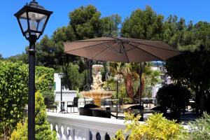 eine Terrasse mit einem Brunnen und einem Sonnenschirm in der Unterkunft Villa Columbus Family Boutique Hotel in Paguera