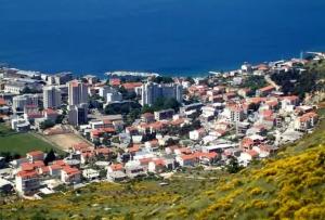 a group of houses on a hill next to the ocean at Apartman Sara in Dugi Rat