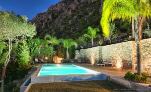 a swimming pool in a garden with a mountain at Villa Mos in Kalamata