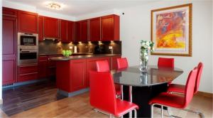 a kitchen with red cabinets and a table with red chairs at Residenz Ambassador B11 in Leukerbad