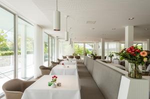 a restaurant with white tables and chairs and flowers at Hotel Berghoeve in Epen