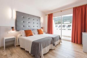 Un dormitorio con una cama grande y una ventana grande. en Typic Oasis Sa Tanca, en Cala Llonga