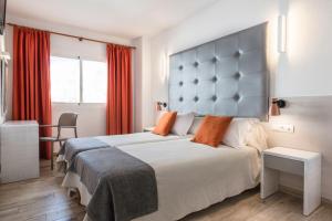 Una habitación de hotel con una cama grande con almohadas naranjas. en Typic Oasis Sa Tanca, en Cala Llonga