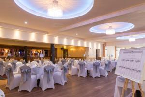 a banquet hall with white tables and chairs and a projection screen at Nithsdale Hotel in Sanquhar