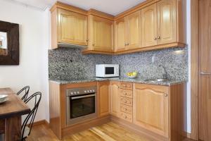 a kitchen with wooden cabinets and a microwave at LLANARS, en Vall de CAMPRODON Vistas Montaña de frente, ASCENSOR, Orientación Sur, Chimenea, WIFI, MOLLÓ PARK, VALLTER, HÍPICA, GOLF in Llanars