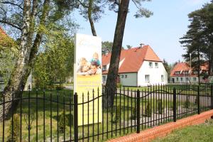 a sign in a park behind a fence at Ośrodek Wypoczynkowy Merkury in Mrzeżyno