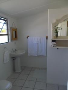 a white bathroom with a sink and a toilet at Breeze Inn Guesthouse in Kiddʼs Beach