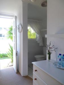 Baño blanco con aseo y lavamanos en Breeze Inn Guesthouse, en Kiddʼs Beach