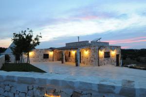 a stone building with a stone wall in front at Il Borgo Delle Querce Villa Fichi Piscina privata in Martina Franca
