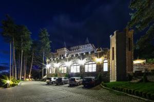 un edificio con auto parcheggiate di fronte ad esso di notte di Valentina Castle a Ognyanovo