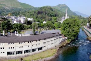 a building next to a river next to a city at Hôtel La Source in Lourdes