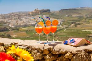 three wine glasses sitting on top of a stone wall at Bellavista Farmhouses Gozo in Xagħra